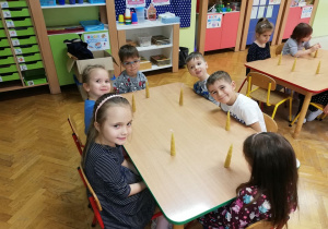 Dzieci siedzą przy stole i oglądają wykonane przez siebie świeczki